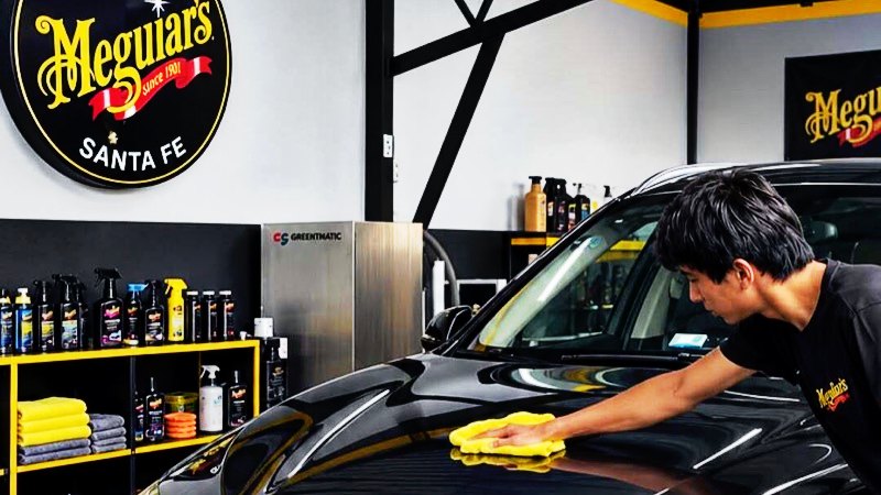 Sucursal Santa Fe: el sello Detail Center Santa Fe en la pared y un detallador encerando una BMW negra
